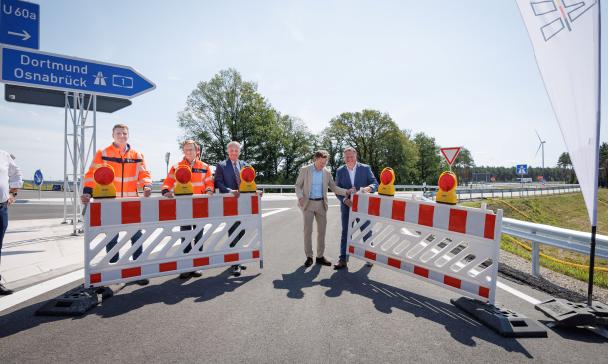 Fünf Personen öffnen einen Straßenbauabsperrung.