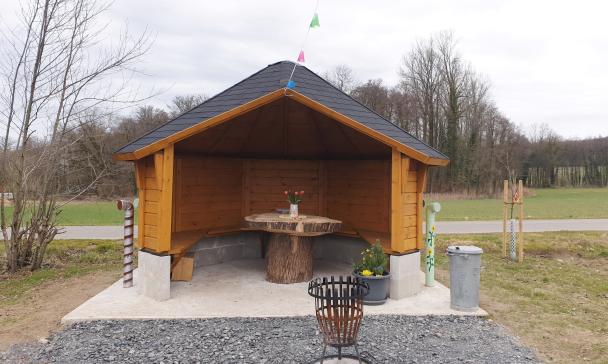 Eine Grillhütte steht in einer Wiesenlandschaft