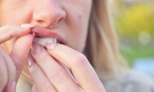 Frau schiebt sich Nicotine Pouches unter die Lippe