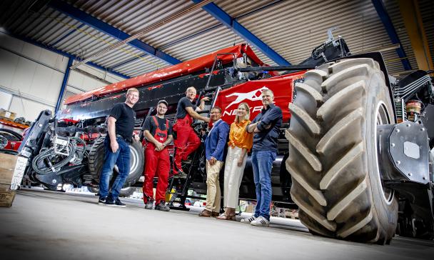 Gruppe von Personen in Halle mit Landmaschinen
