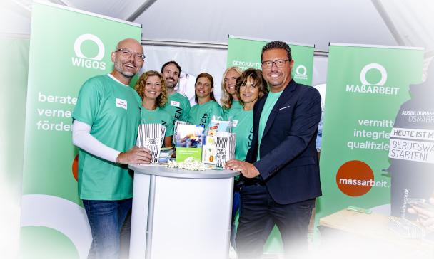 Eine Personengruppe steht an einem Messestand