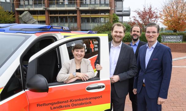 Vier Personen stehen an einem Blaulicht-Fahrzeug.