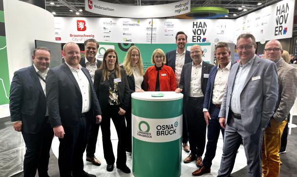 Personengruppe auf einem Messestand schaut in die Kamera.