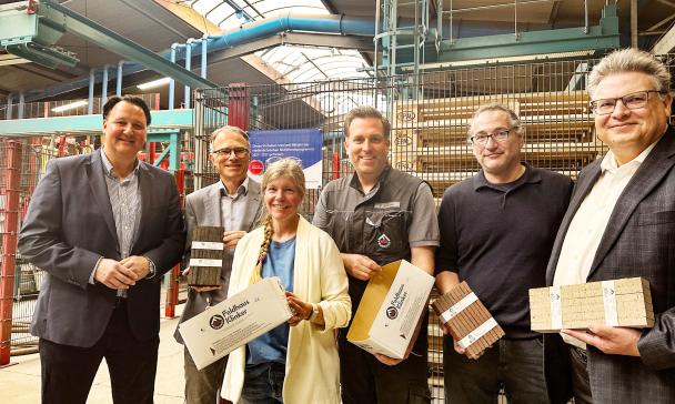 Sechs Personen stehen in einer Werkhalle.