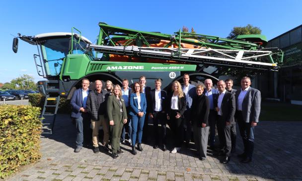 Eine Personengruppe steht vor einer Landmaschine.