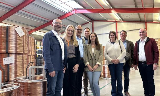 Eine Personengruppe steht in einer Lagerhalle.