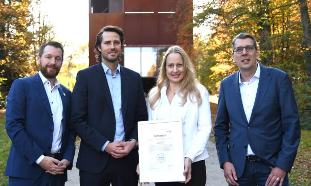 Vier Personen stehen in einem Park.