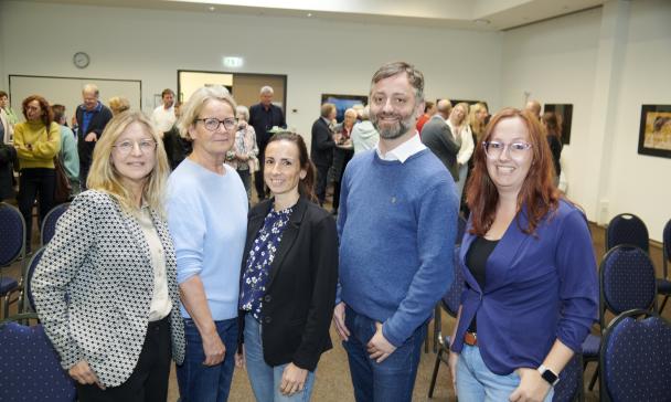 Fünf Personen stehen nebeneinander in einem Raum.