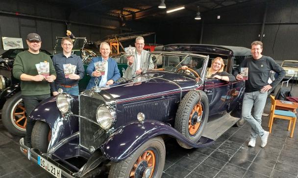Sechs Personen stehen hinter und vor einem Oldtimer.