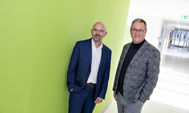 Zwei Personen stehen in einem Gebäudeflur.