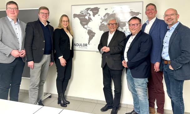 Sieben Personen stehen vor einer Weltkarte.