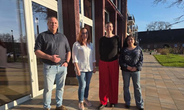 Vier Personen stehen vor einem Gebäude.