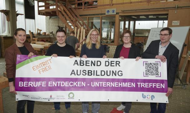 Fünf Personen stehen in einer Werkstatt.