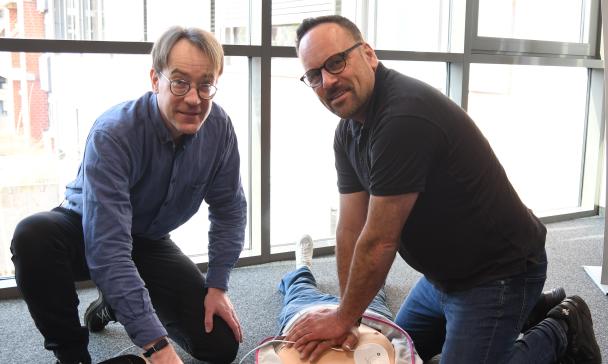 Zwei Personen knien neben einer Puppe an der Wiederbelebung trainiert werden kann.