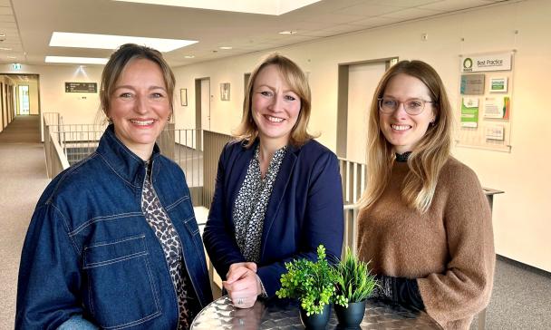 Drei Personen an einem Stehtisch in einem Bürogebäudeflur