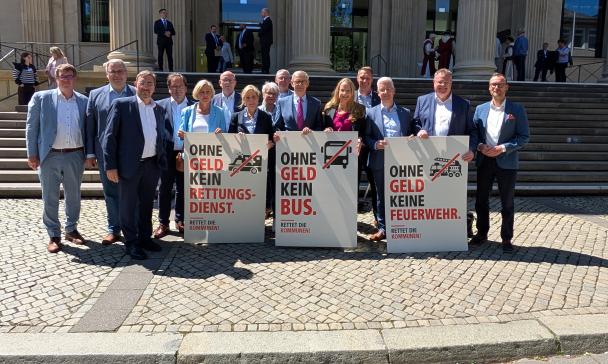 Personengruppe mit Plakaten vor einem Gebäude mit Säulenportal
